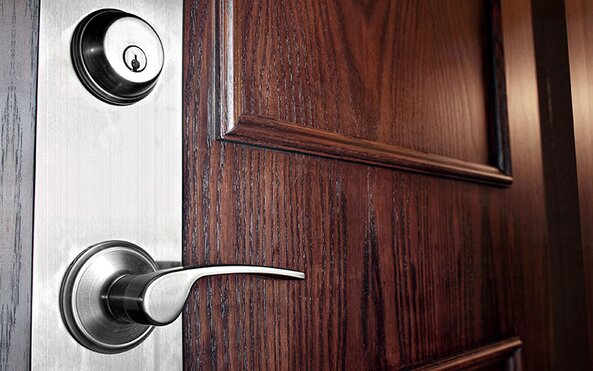 A wooden door with brushed silver locksets.