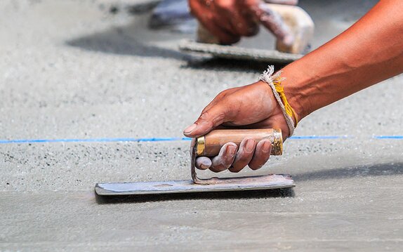 A tradesman using a towel to level concrete.