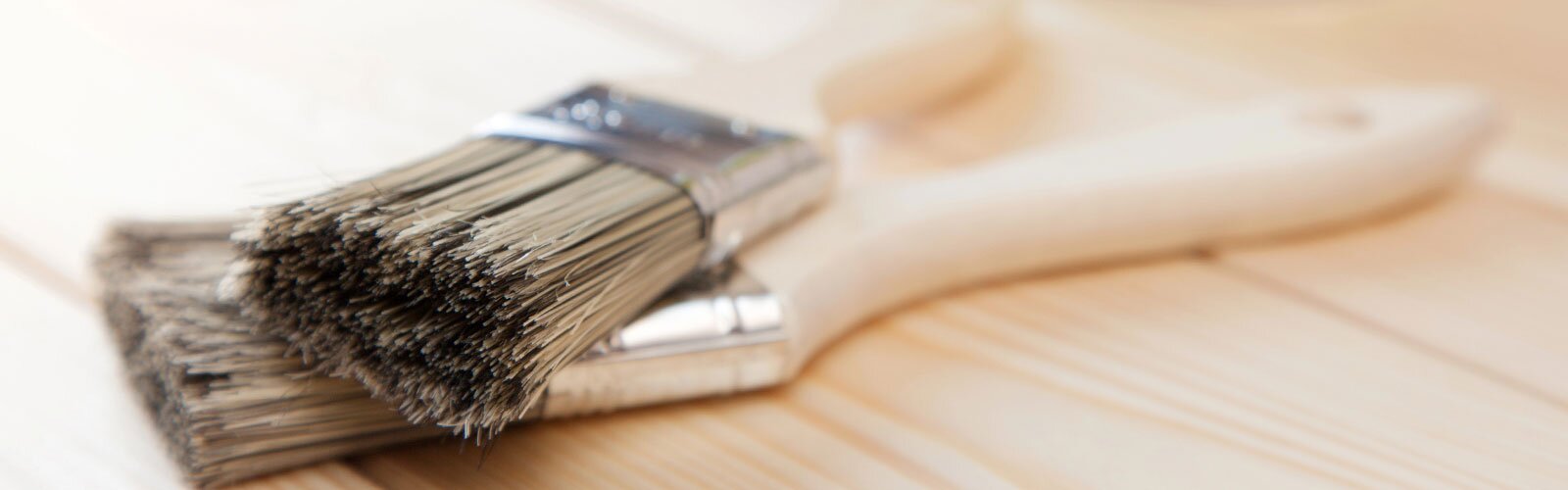 Two paint brushes on a wooden surface.