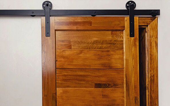 An interior wooden slide barn door with matte black hardware.