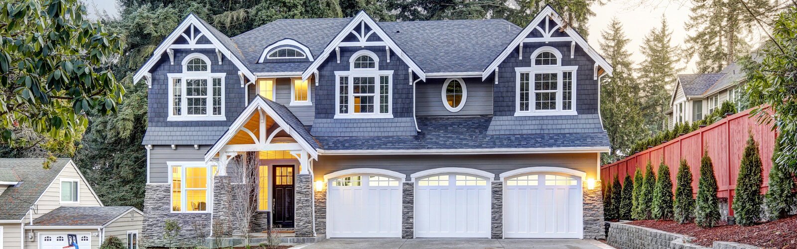 A home exterior with wood siding, stone faux stone veneer, beautiful windows, and a three-car garage.
