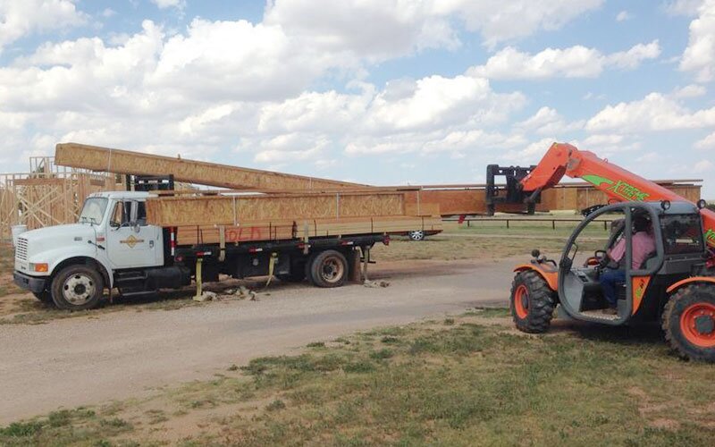 EWP lumber is being unloaded from the delivery truck on site.