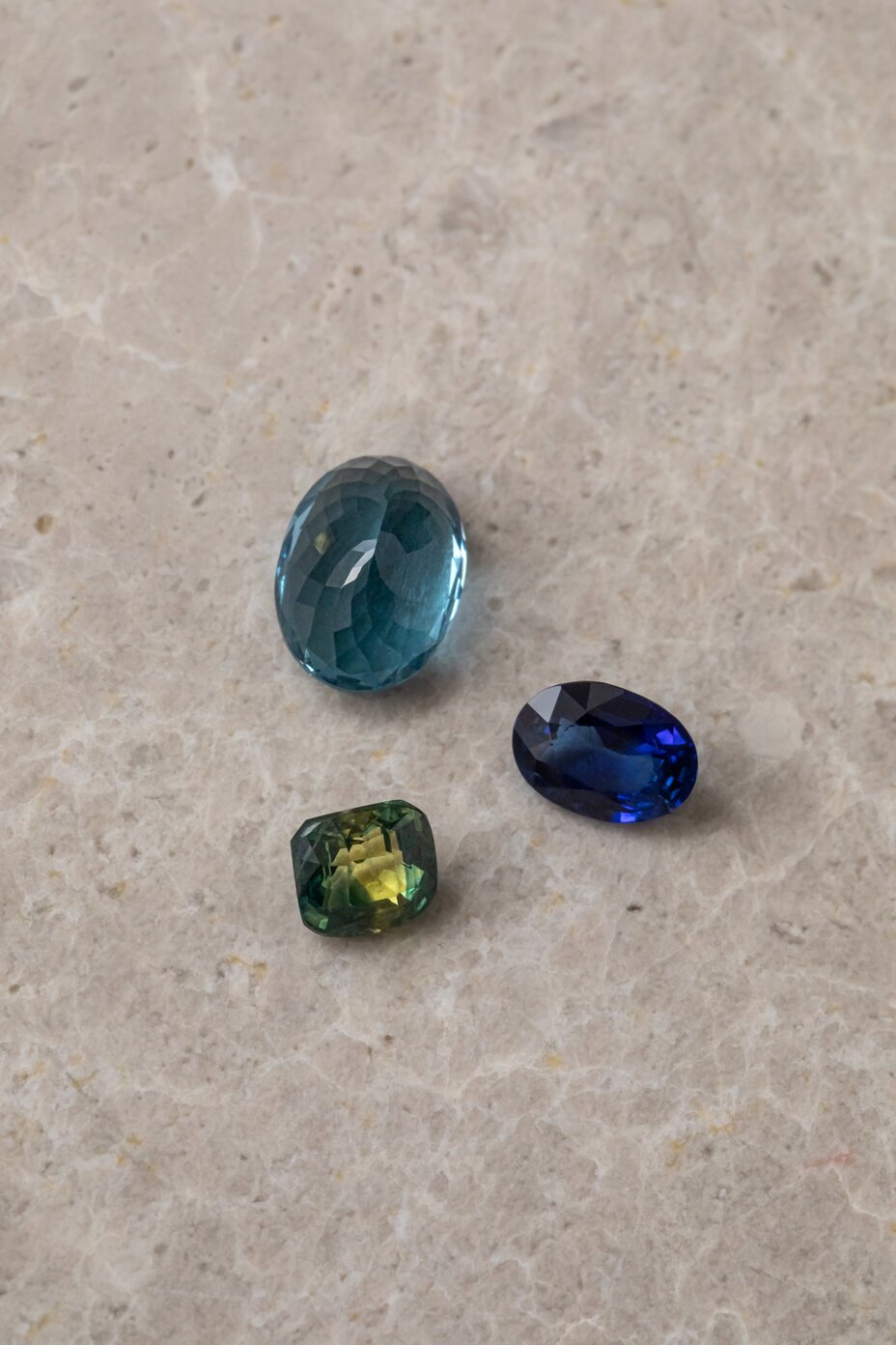 Loose sapphire gemstones in blue, green and teal shades showing colour variations and different cuts