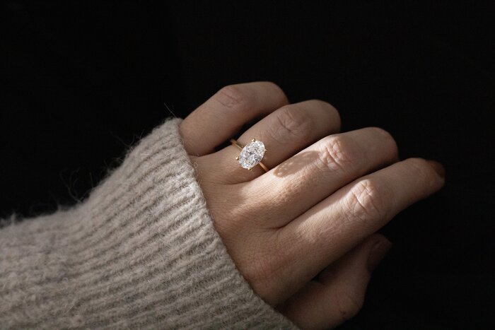 solitaire oval engagement ring in yellow gold on a hand