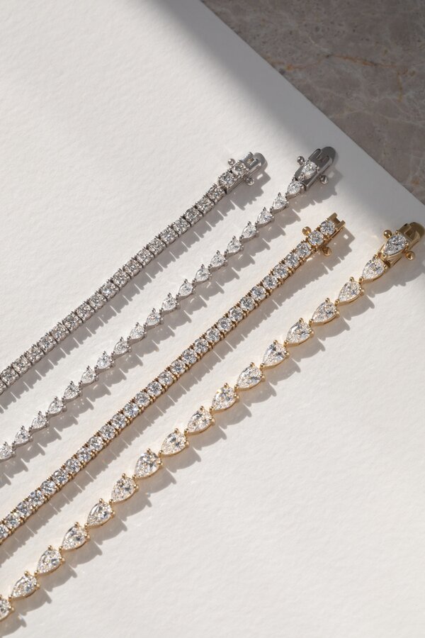 Mixed metal diamond tennis bracelets featuring round and pear-shaped diamonds in classic line settings