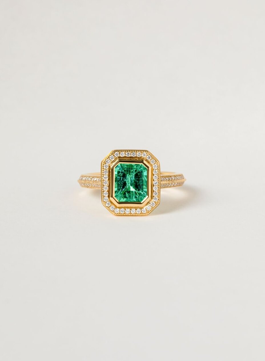 vintage, bezel set, green emerald engagement ring in yellow gold featuring a halo and double pave split by a milgrain detail