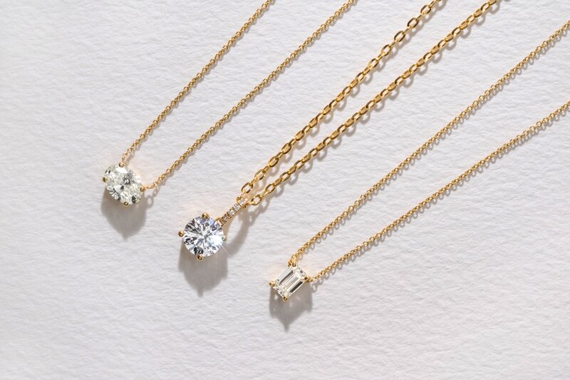 Diamond solitaire pendants in yellow gold including emerald cut, east - west oval and round brilliant diamond designs