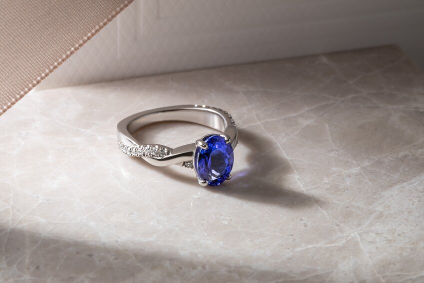 An oval-cut blue tanzanite gemstone ring with a sparkly twisted diamond band