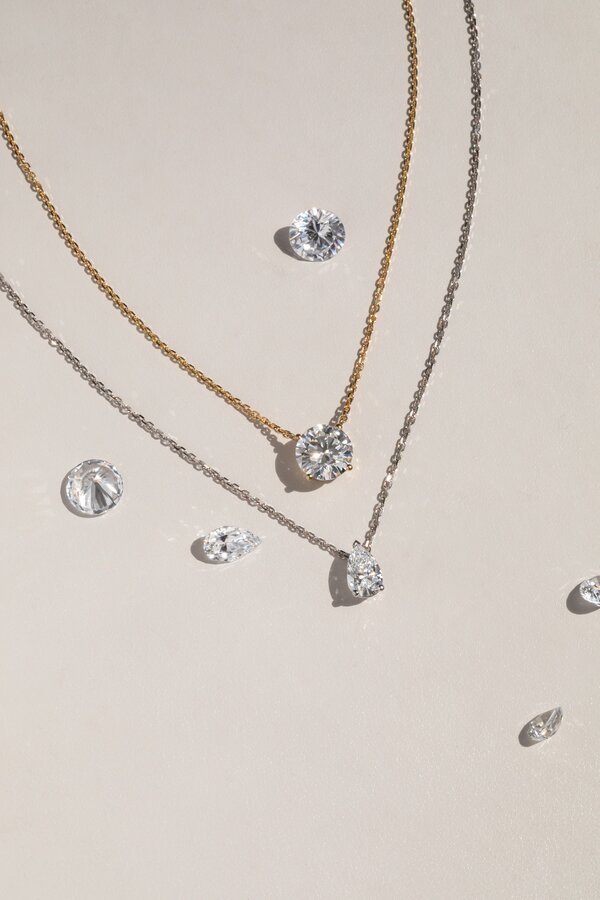 Diamond solitaire pendant necklaces featuring round and pear shaped diamonds on fine chains.