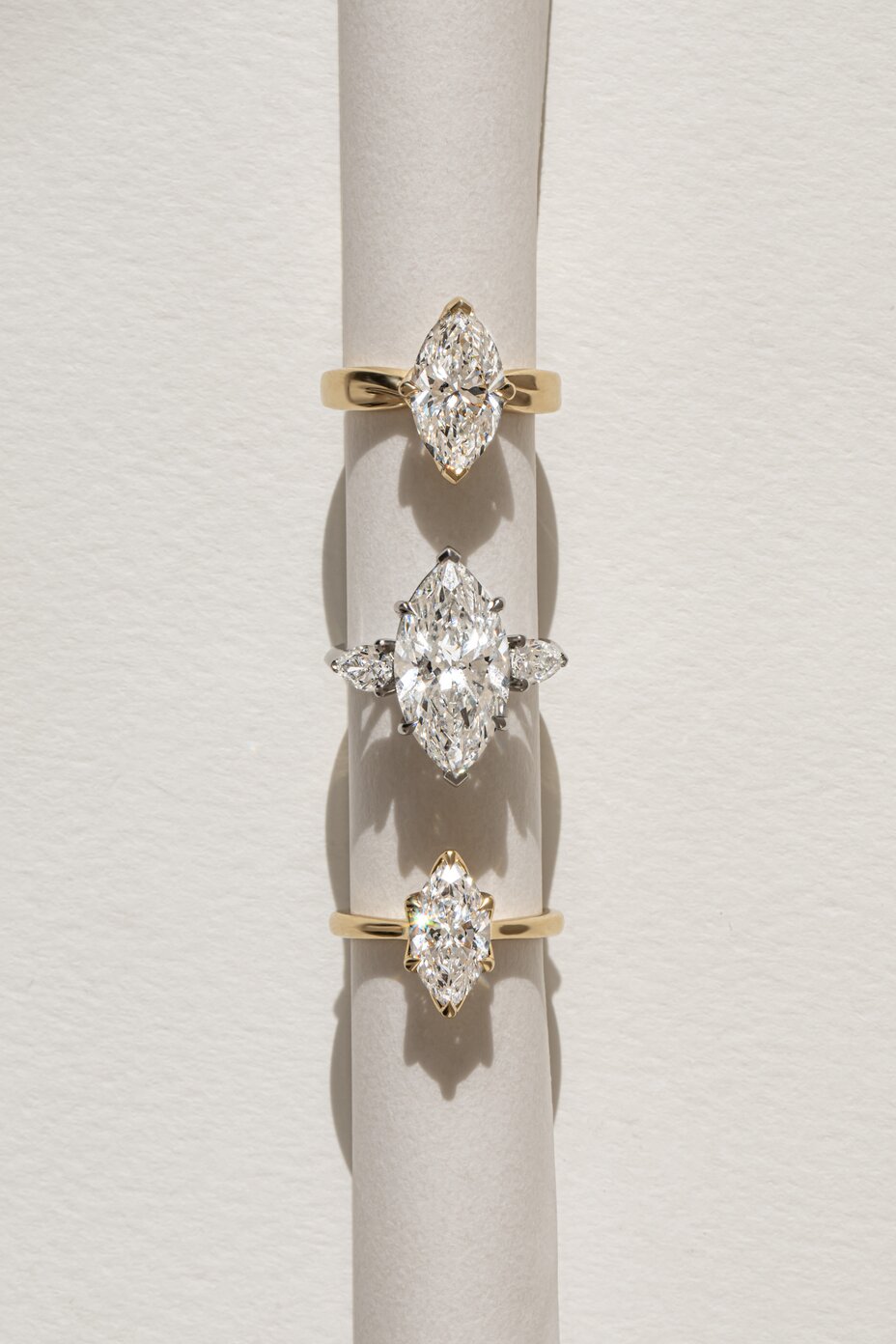 Marquise cut diamond solitaire and three-stone engagement rings in yellow and white gold.