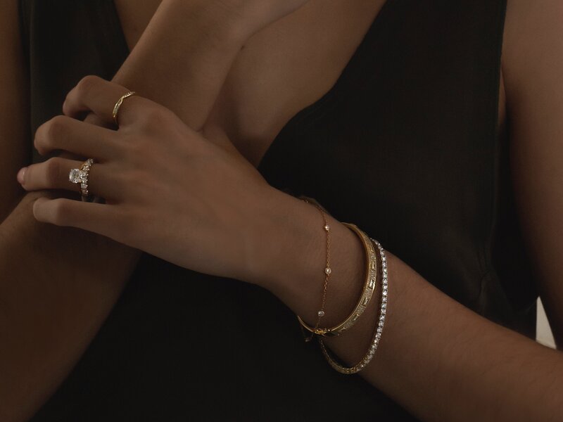 Fashion styling of layered bracelets paired with a diamond ring in various styles on a model’s hand