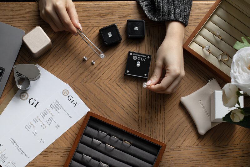 consultation with a jeweller showing multiple loose diamonds, discussing certificates and diamond ring style choices