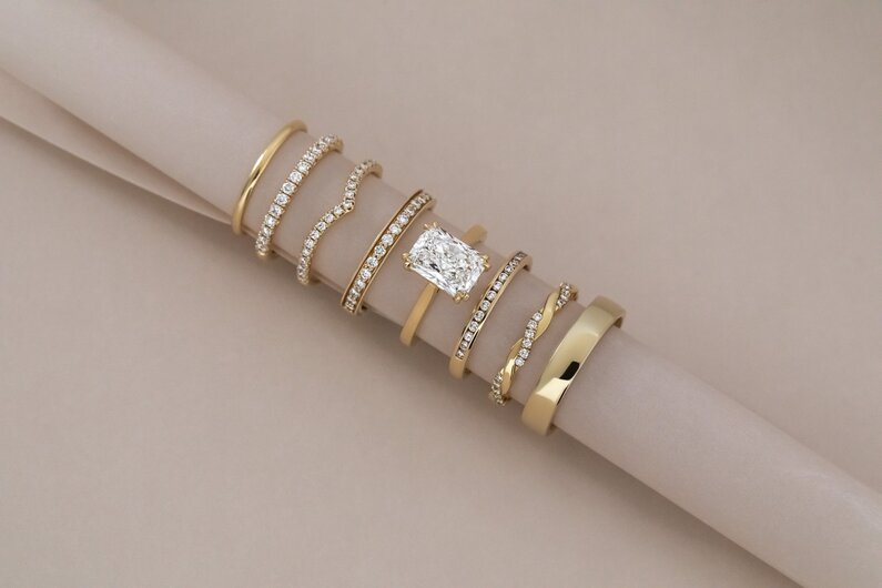 Elegant yellow gold engagement ring styled with layered wedding bands and diamond eternity rings