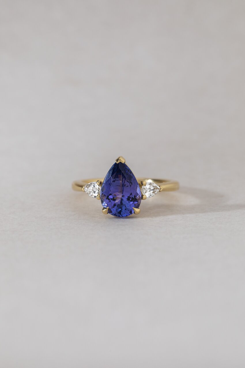 Yellow gold ring featuring a large, pear-shaped blue tanzanite gemstone.