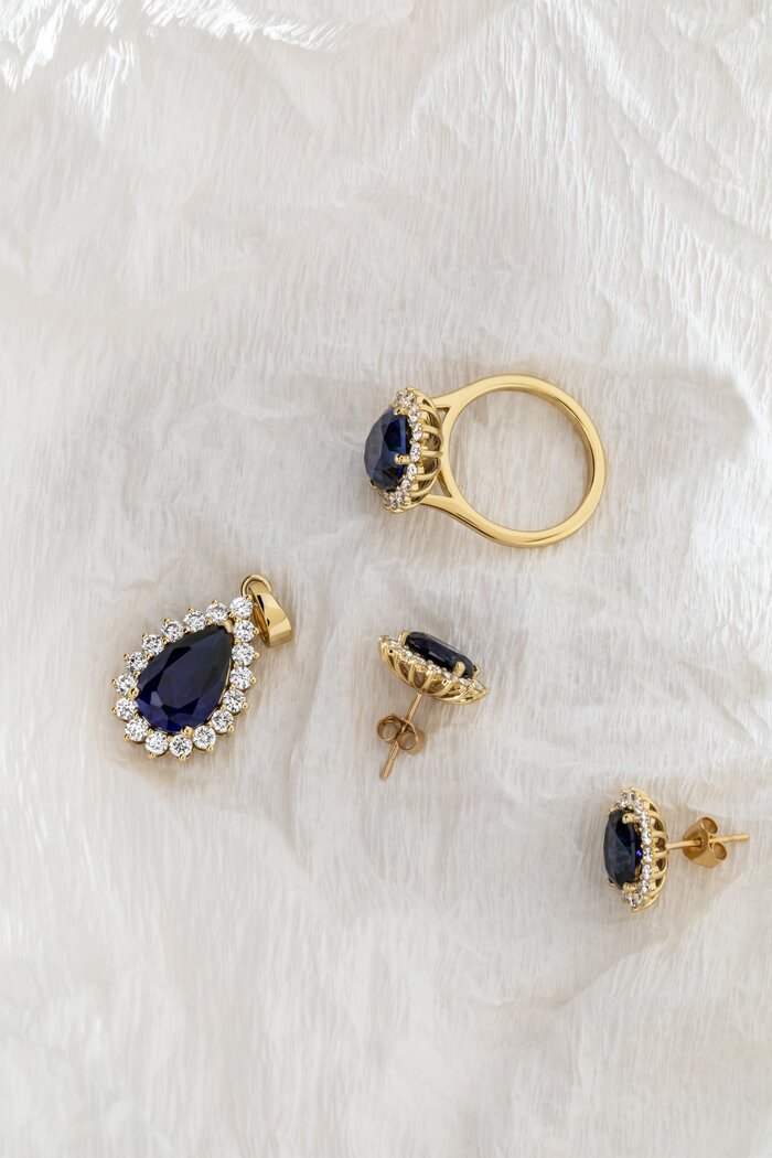 blue sapphire jewellery set in halo style and yellow gold, featuring sapphire earrings, pendant and ring