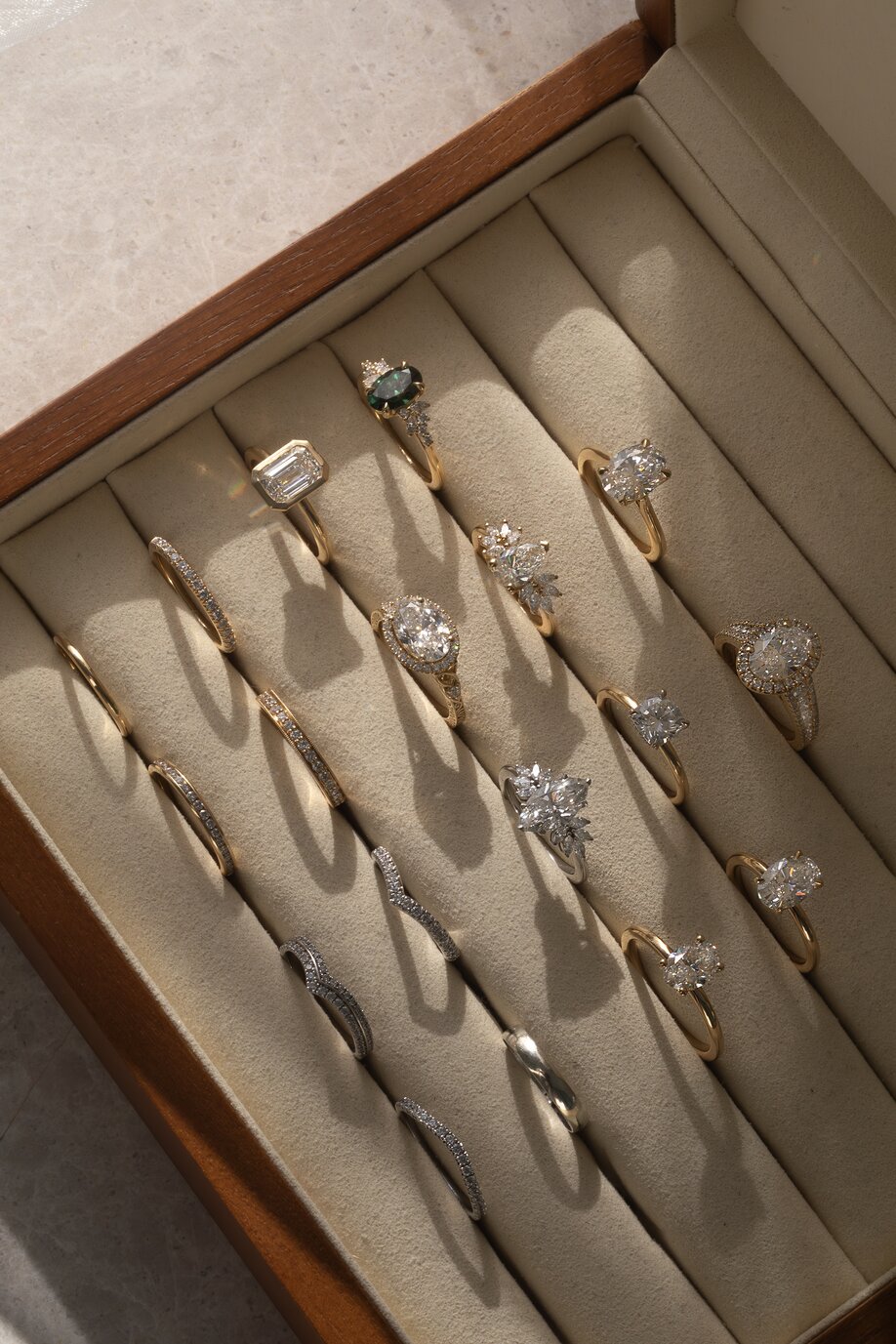 display ring boxed with multiple engagement ring styles and wedding band in mixed precious metals and diamond shapes