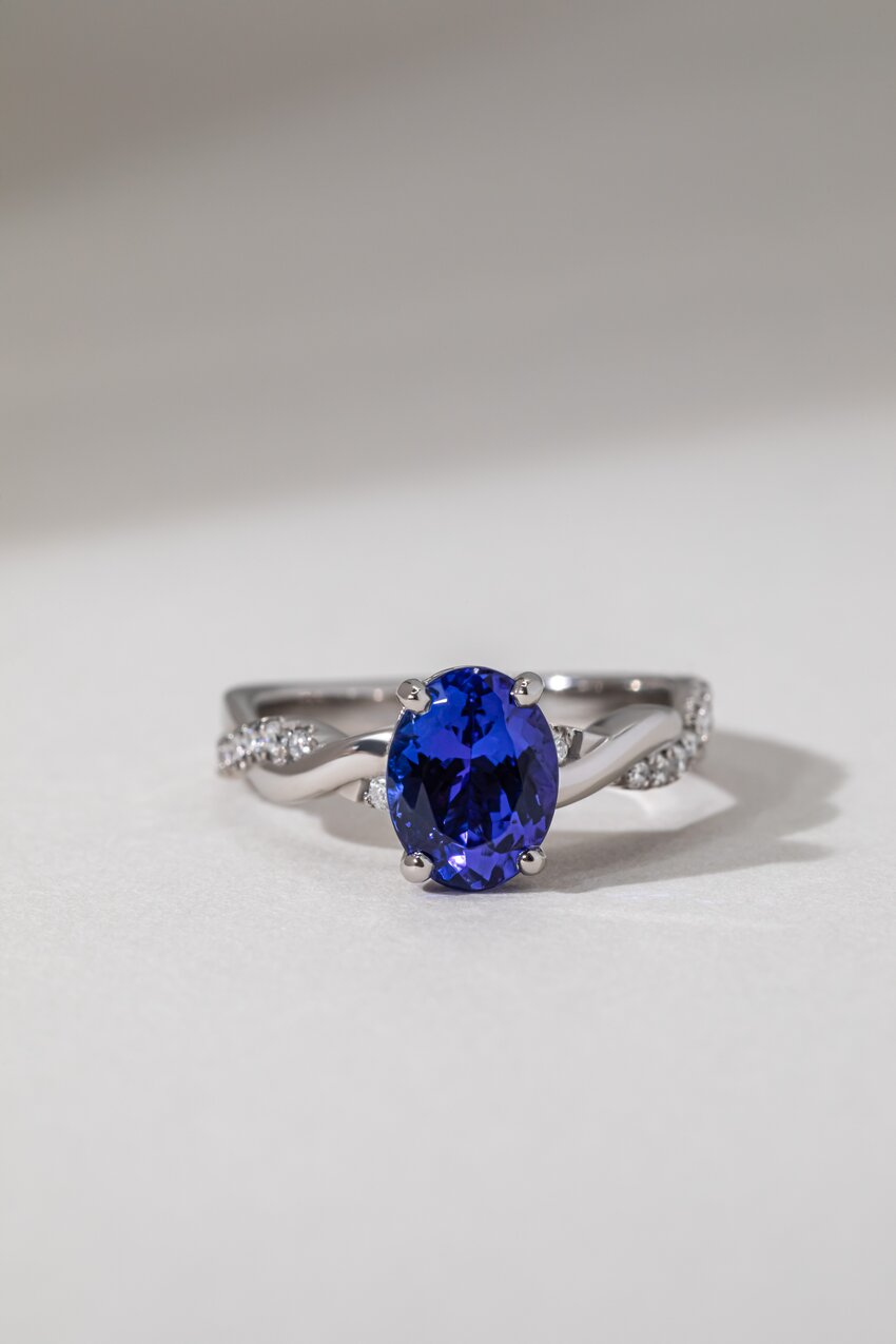 An oval-cut blue tanzanite gemstone ring with a sparkly twisted diamond band