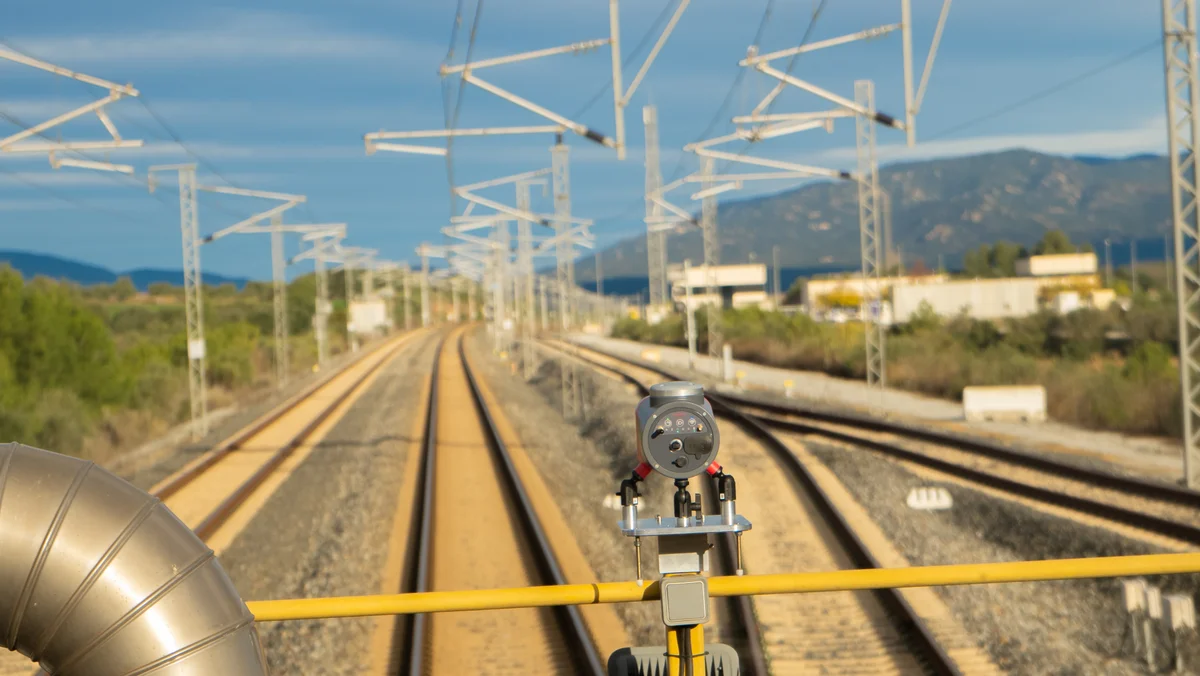 Système de fixation magnétique maintenant un capteur Imajing sur un véhicule ferroviaire au-dessus des voies