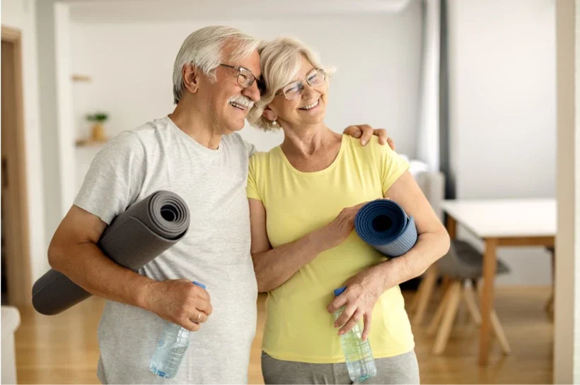Happy mature couple embracing after working out at home.