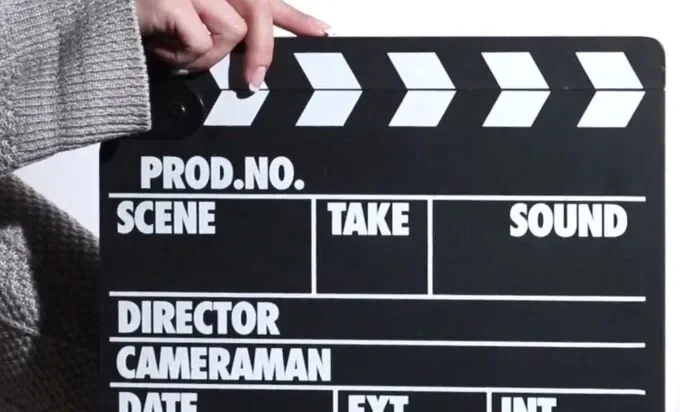 A person holds a clapperboard labeled 