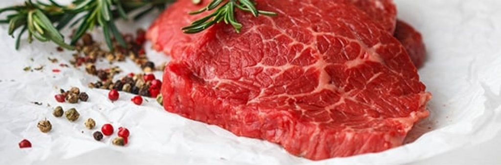 raw steak with rosemary and peppercorns