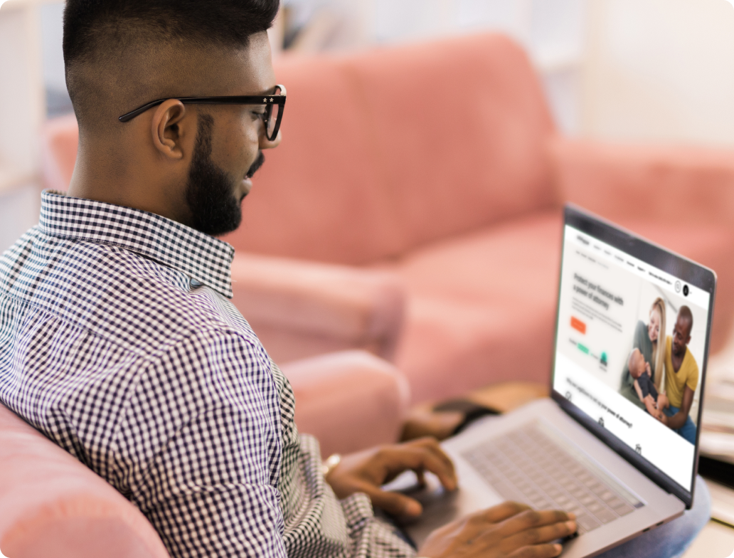 A man in a business casual outfit and glasses uses his laptop.