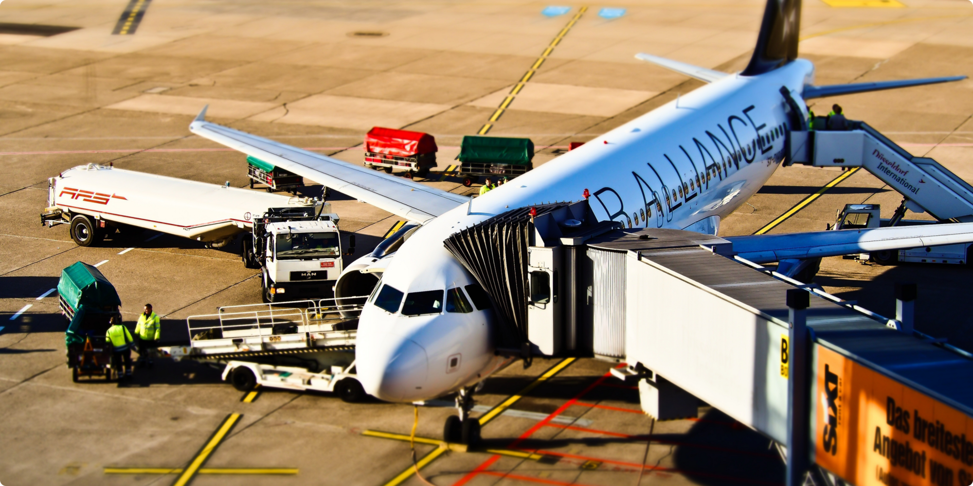 An airplane on the ground with loading equipment and personnel