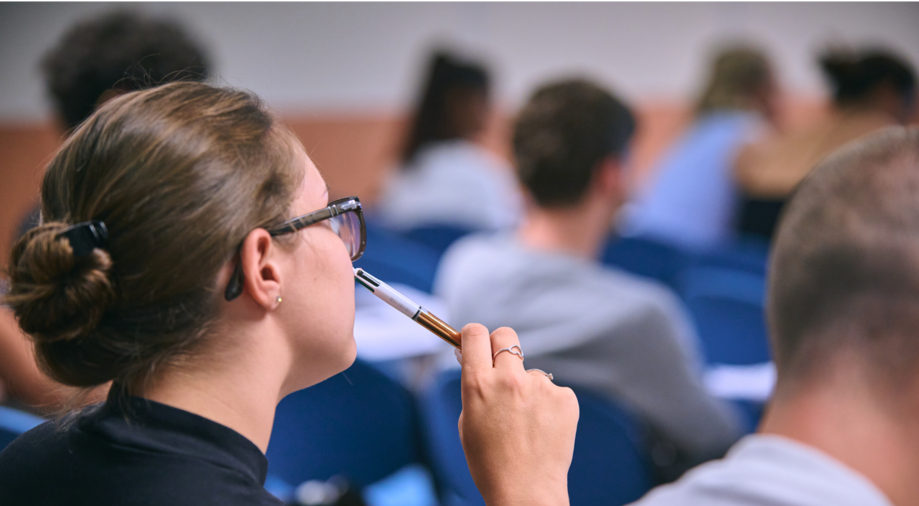 Studentessa al telefono che prende appunti durante una lezione