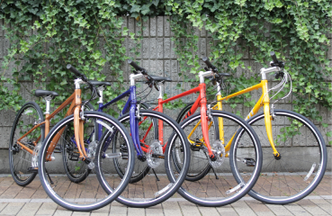 Colorful bicycles lined up against a wall with ivy