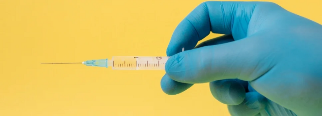 a blue gloved hand holding a syringe and needle