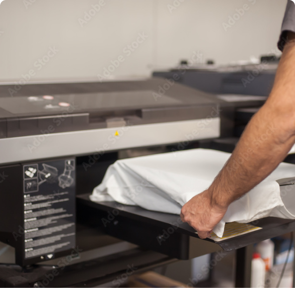 Man placing a white shirt on a printing press. The printing press is a black machine with instructions on the righ side of it. 