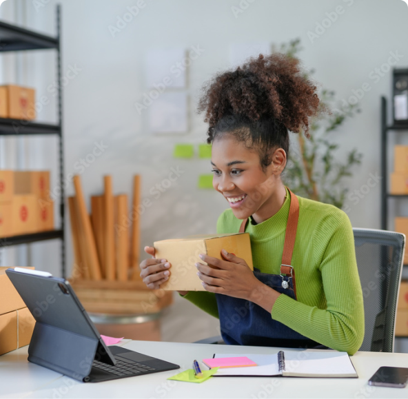 Woman holding a small box, looking at an iPad screen in a warehouse with boxes behind her.