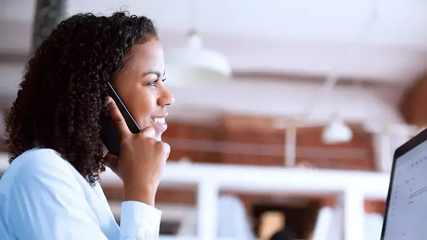 woman-smiling-on-phone-using-computer