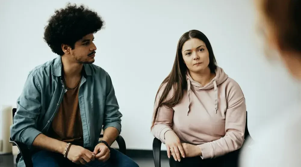 A man and a woman sit in a lawyer's office to discuss contesting a family member's will. 