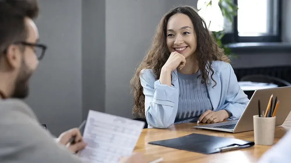 woman in blue suit talking to a man in the office 