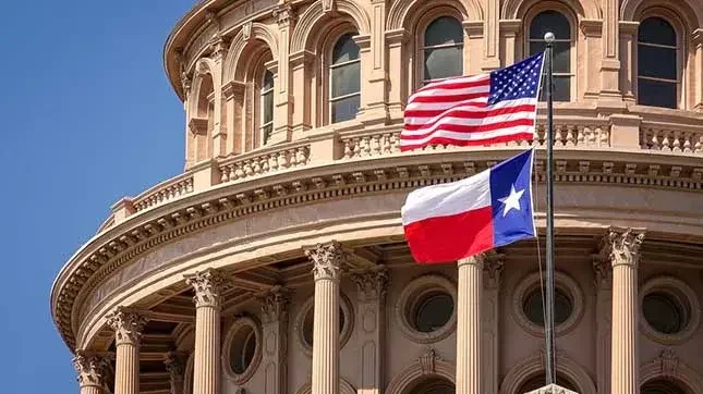 American and Texan flags flying in front of colonnaded building