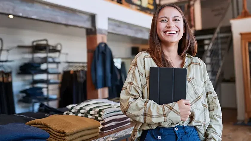 woman in retail store smiling holding a tablet