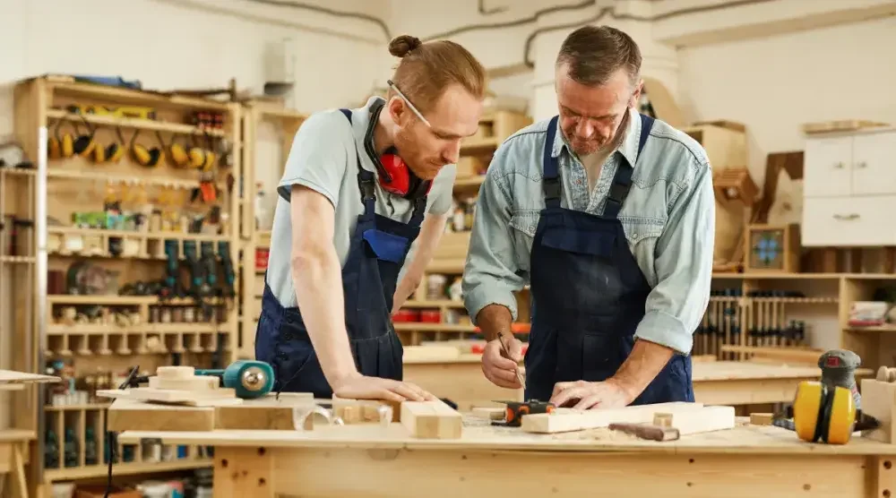 Two veteran business partners work on a project in their carpentry shop.