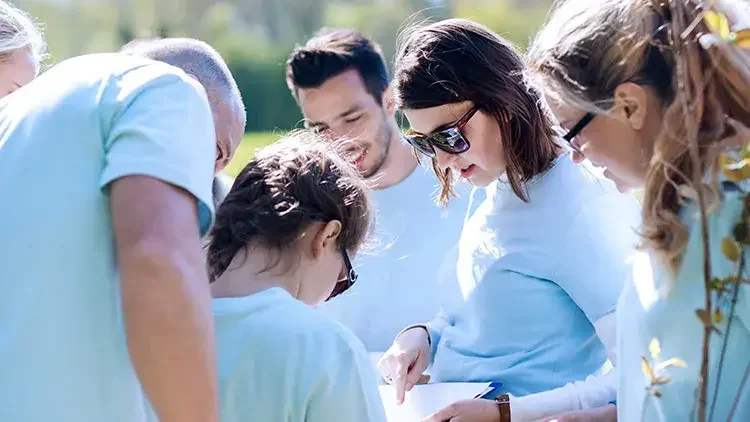 Volunteers gather around woman with clipboard