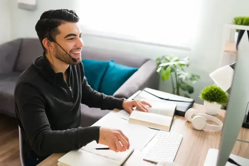 An adult male sitting at a desk in front of a desktop computer. He works from home as an independent contractor.