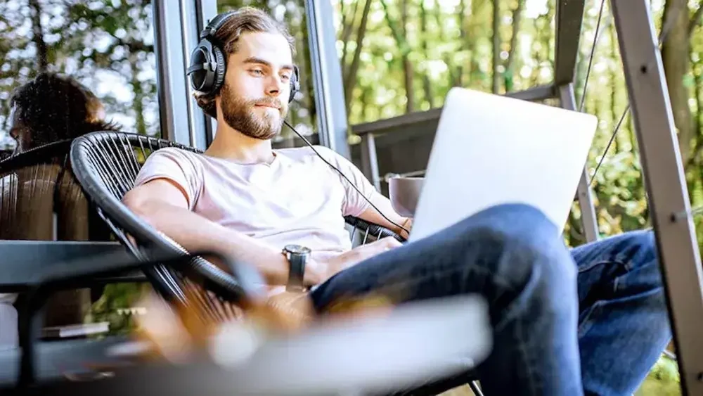 A man wearing headphones looks at his laptop screen as he submits his Certification of Publication to two newspapers. New York has specific publication requirements for LLCs, which mandate publishing a notice or your articles of organization in two designated newspapers for six consecutive weeks.