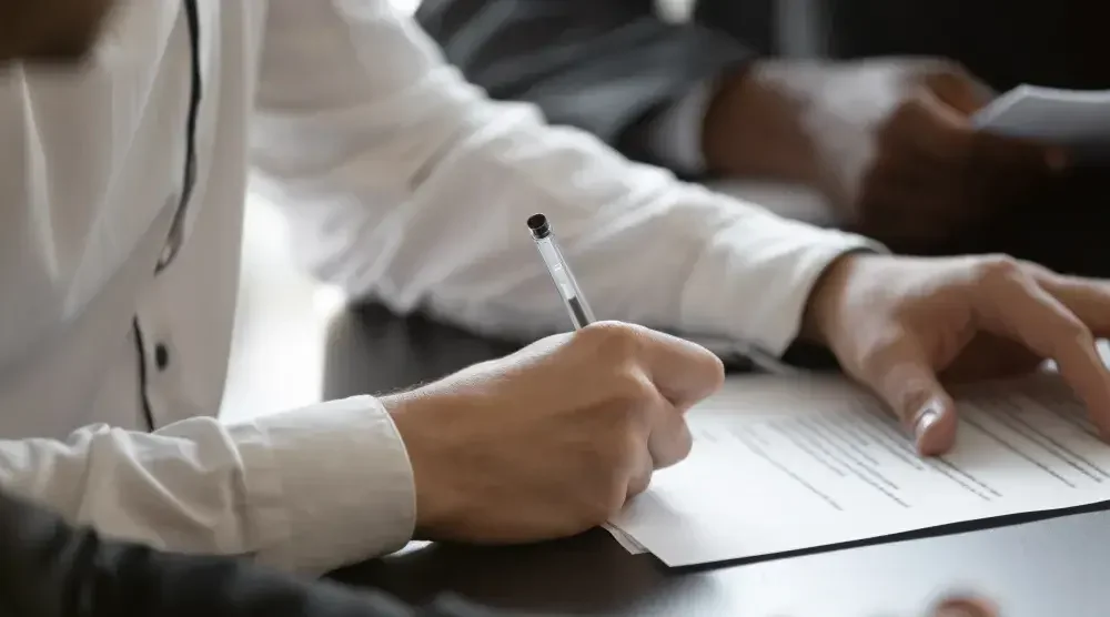 A person sitting at a table filling out a form for a business license in California