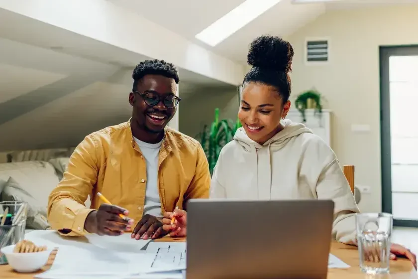 Co-owners of a small business sit at a desk in their office and change the name of their business online.