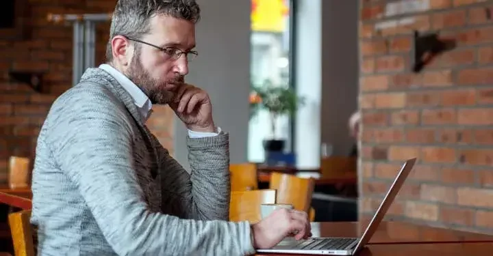 Man in café looking intently at laptop