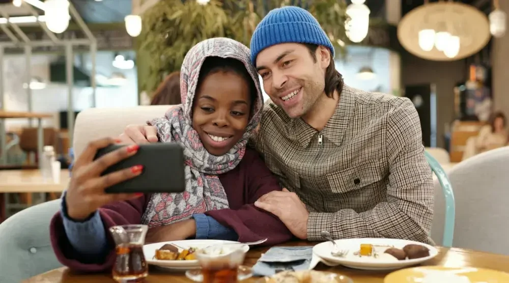 A couple takes a selfie while eating breakfast in a cafe.