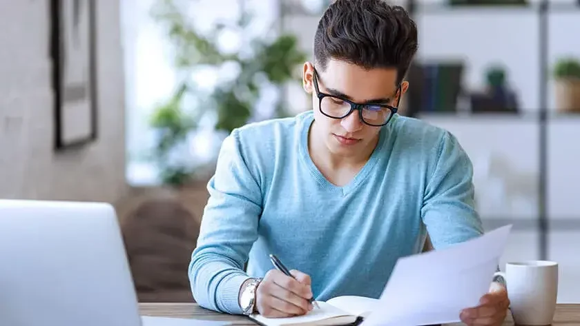 young man writing in notebook