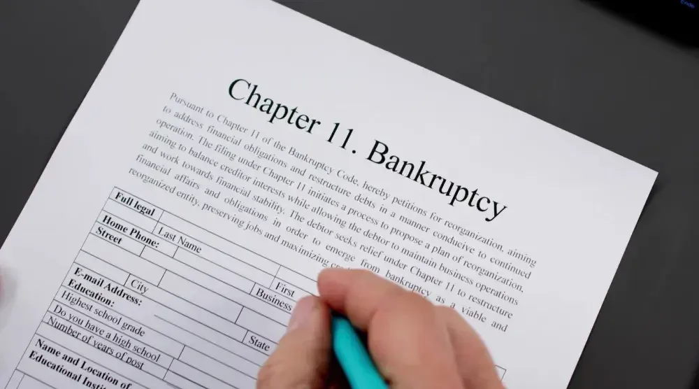 A person filing for Chapter 11 bankruptcy signs documents. Chapter 11 bankruptcy is a legal mechanism for financial reorganization. It is commonly used by businesses.