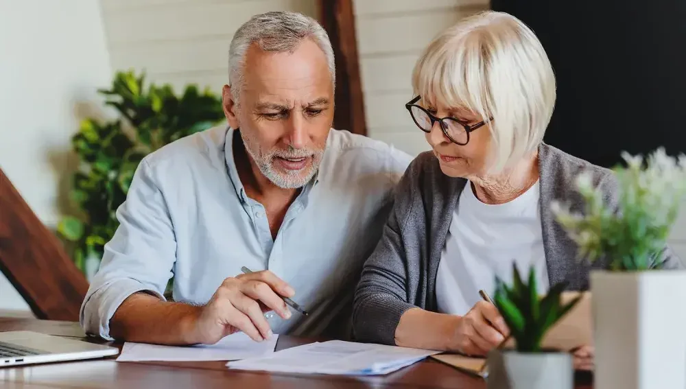 A couple sits together in their home to make firm plans as they near retirement. 