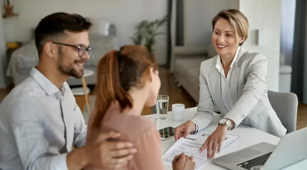 A woman reviews a power of attorney letter while her lawyer explains certain points and her supportive husband watches on.