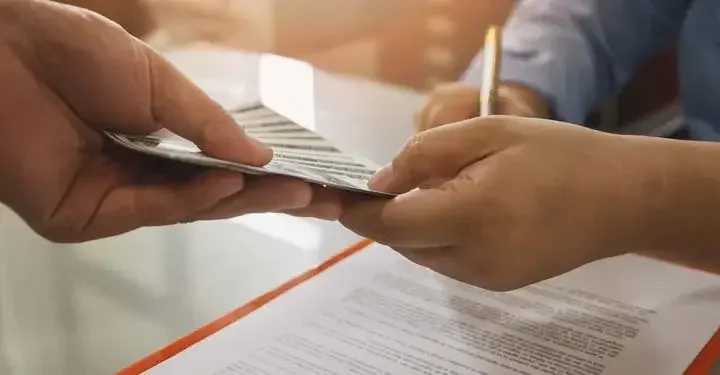 Man handing tickets to woman over paper as she signs document